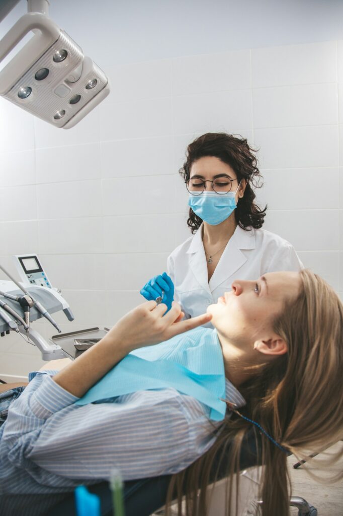 Female dentist examining patient on dentist chair.